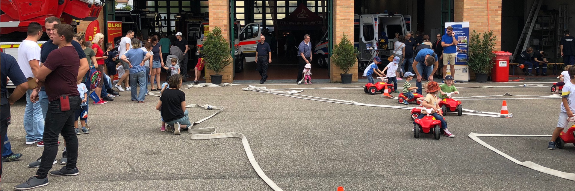 Bild von einem vergangenen Tag der offenen Tür bei der Feuerwehr Ludwigsburg, Innenhof mit Kindern und Löschschläuchen