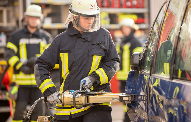 Feuerwehrfrau schneide mit Spezialwerkzeug eine Autotür auf